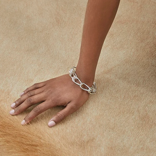 Sterling Silver chain bracelet on a wrist against a beige background