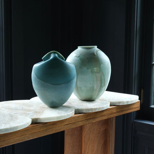 Two ceramic vases on a wooden surface with a dark background
