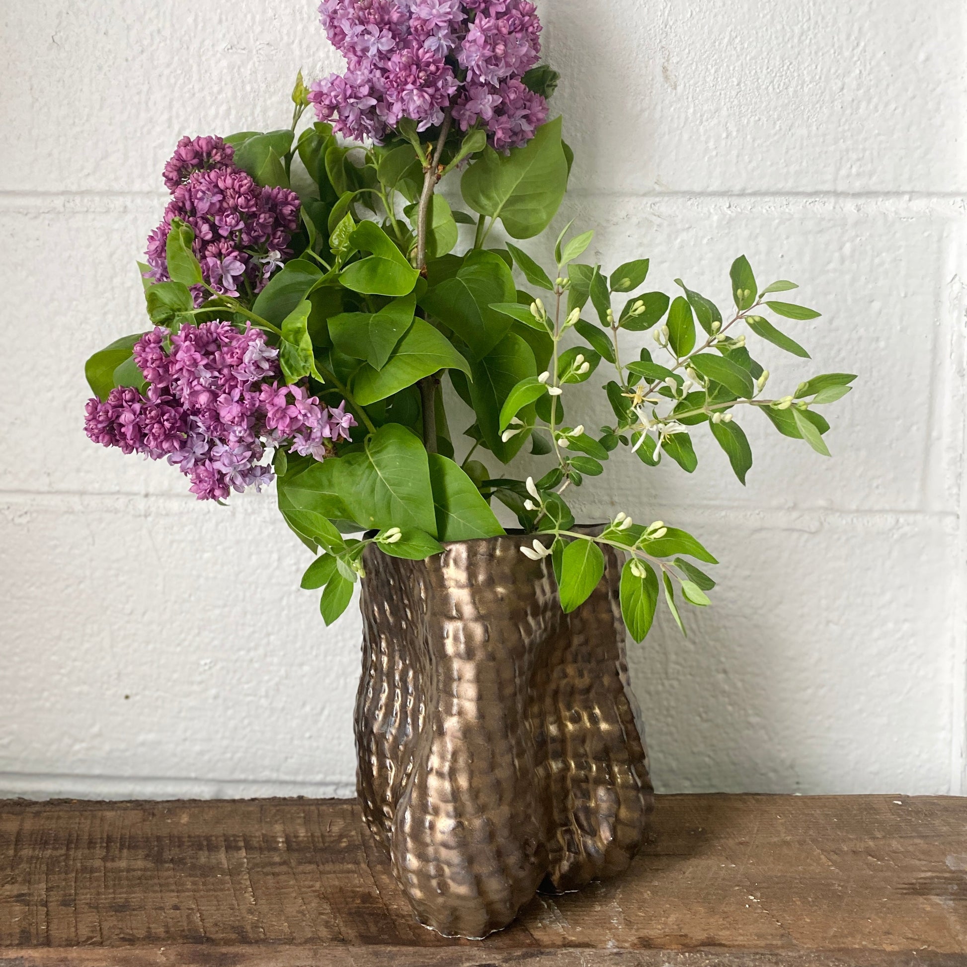 Bouquet of purple flowers in a textured bronze vase by Sarah Mijares Fick